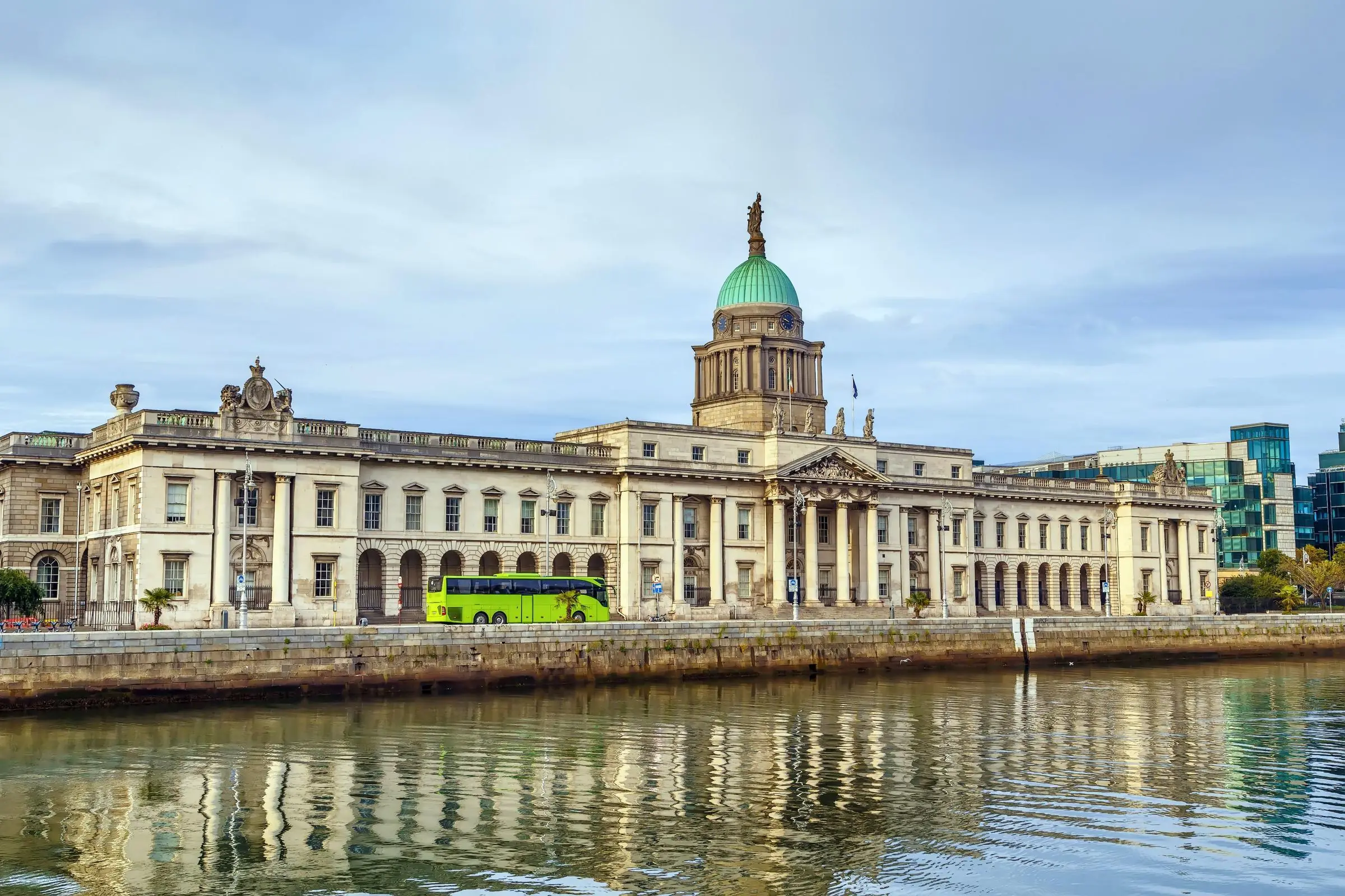 The neoclassical facade of the Custom House reflecting on the River Liffey at dusk